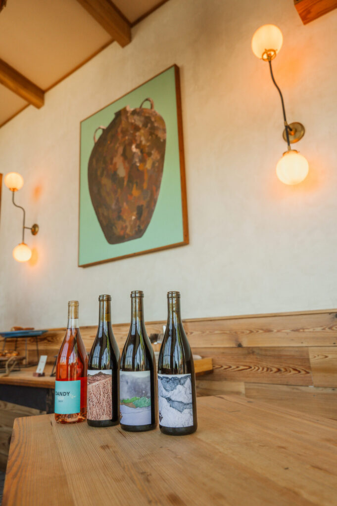 Spring 2026 release bottles on a wood table beneath original artwork