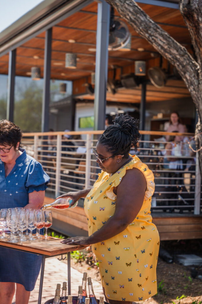 Team member pouring rosé at the welcome table during the Spring 2026 release